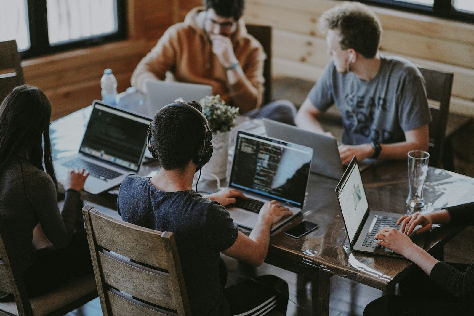 People working on laptops around a shared wooden table